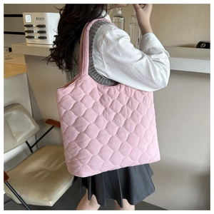 Pink quilted tote bag with diamond pattern shown in a lifestyle commuting scene