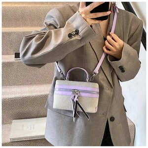 Detail of canvas mini box bag with purple leather trim and crossbody strap