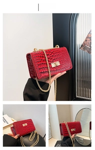 Détail du sac à main rouge à motif crocodile avec fermoir doré et bandoulière chaîne