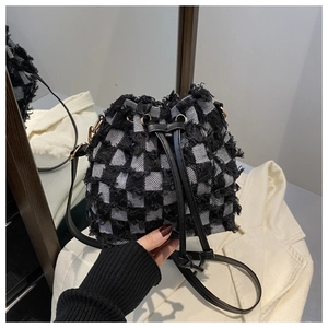 Macro detail of checkered tweed bucket bag with fringe trim and leather drawstring closure