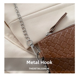 Detail of silver hardware hook and metal chain on brown woven texture envelope bag