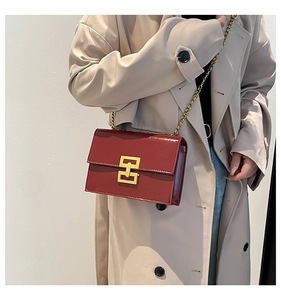 Detail of burgundy patent leather square bag with gold H-buckle and elegant chain strap
