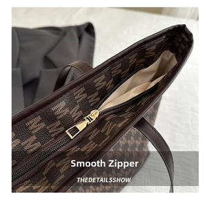 Close-up of golden zipper closure and monogram print on the brown tote bag