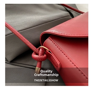 Detail of dark red leather handbag showing fine stitching and metal ring buckle hardware