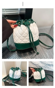 Close-up of quilted white leather drawstring bucket bag with green trim and chain strap