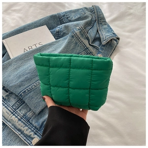Detailed view of emerald green quilted pouch bag with soft nylon padding and hand-held texture