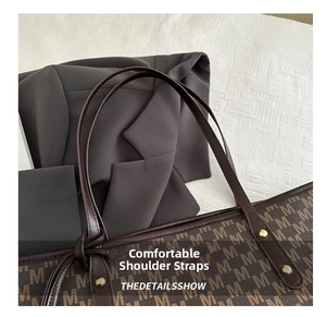 Close-up of brown monogram tote bag strap attachment with golden metal rivets