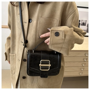 Détail d'un sac bandoulière chic en cuir noir avec boucle métallique dorée