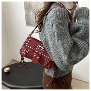 Détail du sac à bandoulière en cuir bordeaux avec rivets argentés et boucles punk