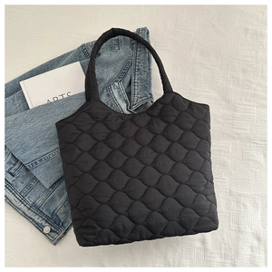 Detail shot of black quilted shoulder bag with scalloped stitching on denim jacket