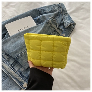 Detail of a bright yellow quilted puffy handbag with soft texture and vibrant finish