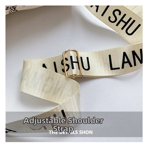 Detail of adjustable cream shoulder strap with black lettering and gold buckle