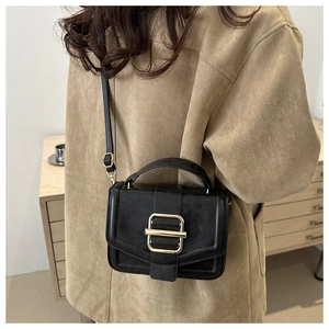 Détail du sac en cuir noir avec boucle dorée carrée et poignée supérieure robuste