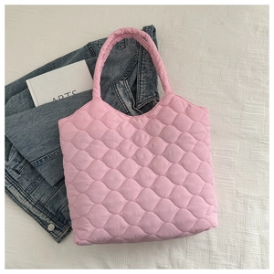 Detailed top view of a pink quilted puffer tote bag with soft embroidery on white fabric