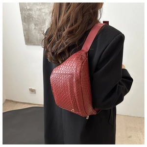 Detail of burgundy woven texture chest bag with wide fabric strap on black blazer