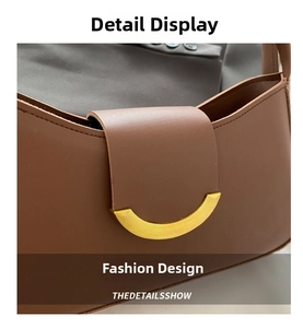 Detail shot of a brown leather shoulder bag featuring a gold half-moon metal buckle