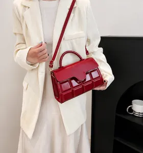 Detail of burgundy crossbody bag with chocolate pattern texture and curved handle