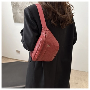 Detail of burgundy woven crossbody bag featuring textured PU leather and golden zipper hardware