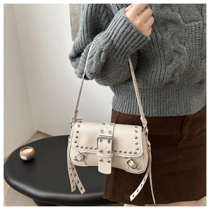 Detail of off-white shoulder bag featuring silver rivets and metallic buckle closure