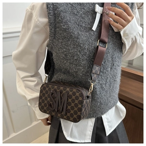 Detail of camera bag with wide strap and raised SM letters in brown monogram leather