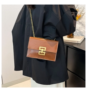 Detail view of a vintage brown leather shoulder bag with gold chain and metal buckle