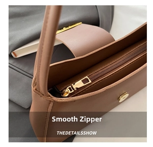 Close-up of caramel leather underarm bag with metal zipper and magnetic snap closure