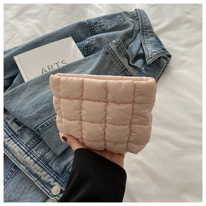 Close-up of pink quilted makeup bag with square embossed pattern held in hand