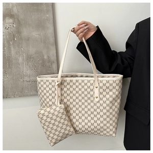 Close-up of beige tote bag with M-letter pattern, small pouch, and gold hardware details