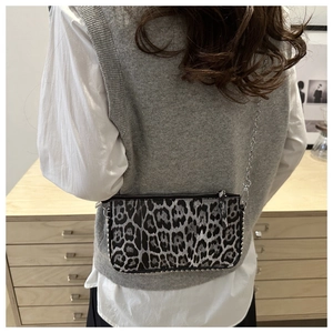 Close-up of leopard print crossbody bag featuring silver studs and a metallic chain strap