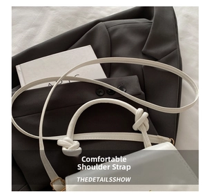 Detail of white leather shoulder bag featuring a slim strap with stylish knot design