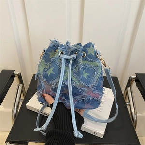 Tie-dye denim bucket bag featuring distressed fringe and star print in a lifestyle setting