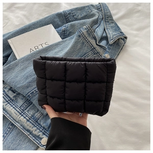 Close-up of black quilted puffer clutch bag with square embroidery and soft texture