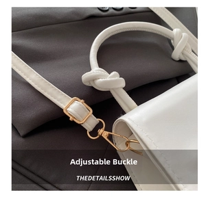 Detail of white leather handbag with golden adjustable buckle and knotted strap design