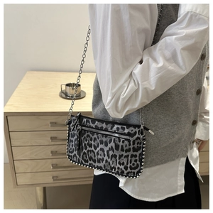 Detail of silver rivets and front zipper pocket on leopard print crossbody chain bag