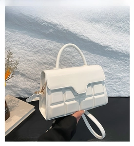 Detailed view of white PU leather handbag with chocolate cube embossed texture and gold hardware