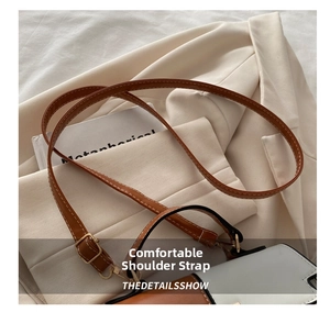 Détail de la bandoulière en cuir contrasté avec boucle dorée sur un sac à main chic