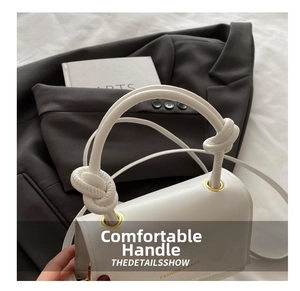 Detail of the white leather bag featuring a unique thick rope knotted handle and metal eyelets