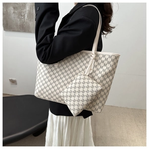 Detail of beige monogram tote bag set with matching pouch worn with formal outfit