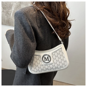Detailed view of white hobo bag with M-pattern print and silver metal logo on model