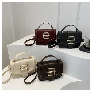 Detail view of four vintage leather crossbody bags with large gold square metal buckles