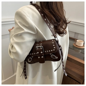 Detail of dark brown leather rivet bag featuring silver metal eyelets and adjustable strap