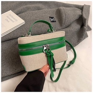Detail of dual zipper closure and green leather trim on contrast weave box bag