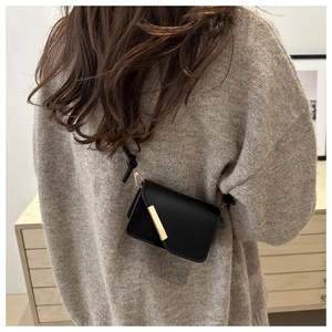 Dettaglio della borsa a tracolla minimalista in pelle nera con finiture d'oro