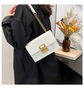 Close-up of white leather shoulder bag featuring elegant gold geometric metal clasp