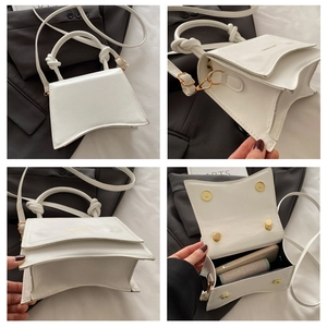 Detail view of white minimalist handbag showing curved base and internal storage capacity