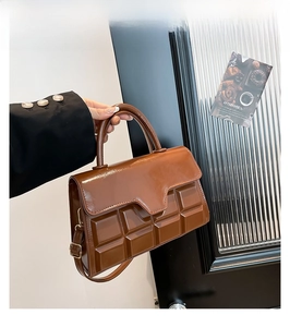 Detail of a brown handbag with chocolate embossed texture and elegant gold hardware