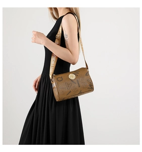 Détail d'un sac cylindre en cuir marron avec large bandoulière imprimée porté par un mannequin