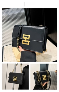 Detail of glossy black leather crossbody bag featuring a golden geometric clasp and chain strap