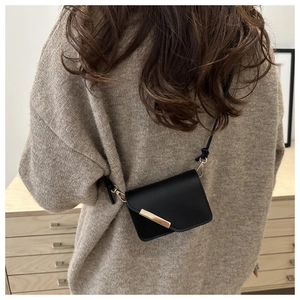 Dettaglio di una mini borsa a tracolla nera con finiture in metallo dorato su un modello