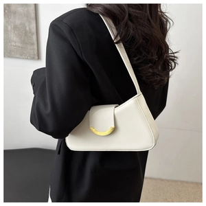 Side view of cream leather underarm bag with gold metal buckle worn by a model